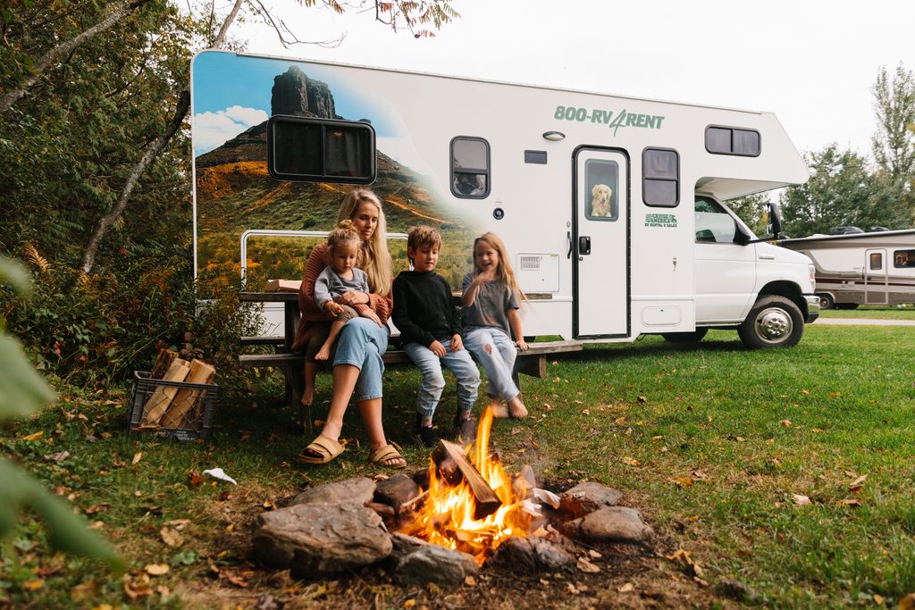 Family enjoying a campfire beside a Cruise America RV